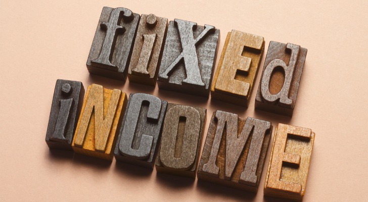 A close-up of the words "fixed income" is spelled out using carved wooden blocks.