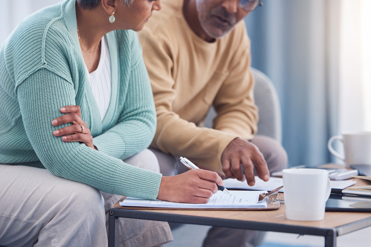 A senior couple signs paperwork for their retirement plan.