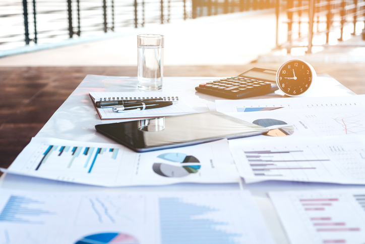 Closeup of a calculator and tablet resting on a finance report.